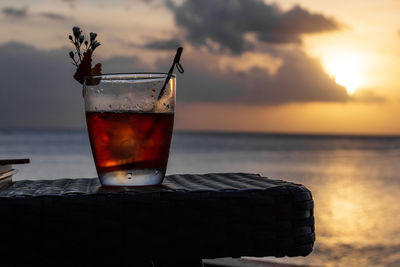 Drink on table against sea during sunset