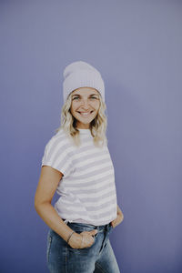 Portrait of young woman standing against blue background