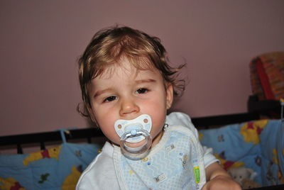 Portrait of baby boy sucking pacifier at home