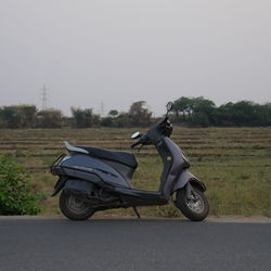 Side view of motor scooter parked on road against sky