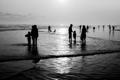 Silhouette people on beach against sky