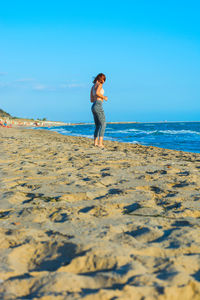Full length of woman standing on shore at beach against sky