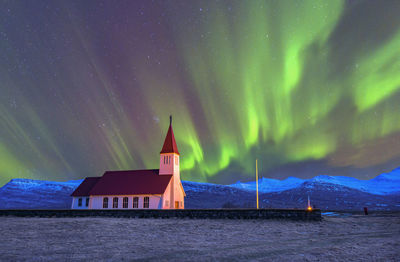 Aurora polaris over church against sky at night