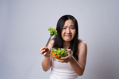 Portrait of woman holding food against white background