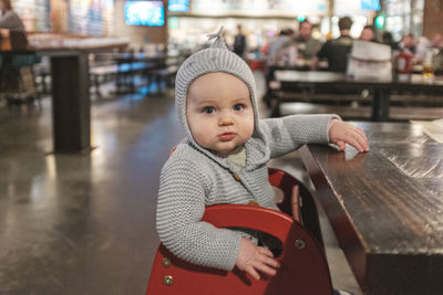 Portrait of cute baby boy sitting in restaurant