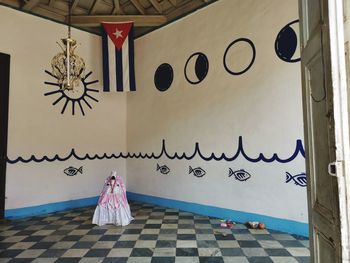 Rear view of woman walking on tiled floor against wall