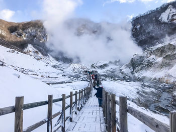 Rear view of people on snow covered mountain against sky