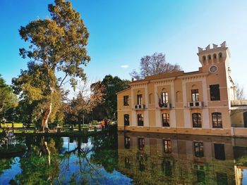 Building by lake against sky during autumn