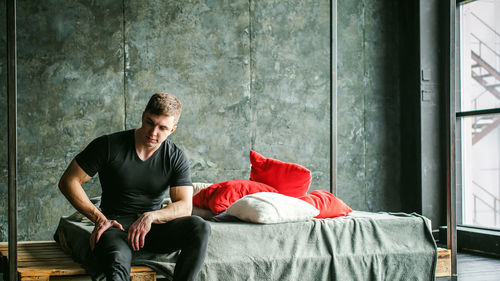 Muscular man sitting on bed at home