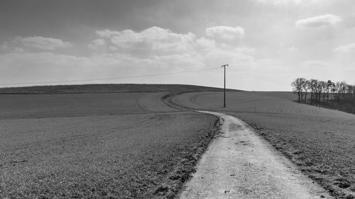 Empty road on field against sky