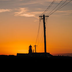 Silhouette electricity pylon against romantic sky at sunset