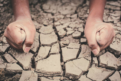 High angle view of cropped hands on barren ground