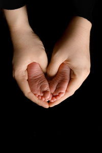 Cropped hand of person gesturing against black background