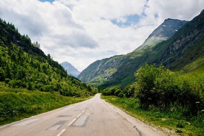 Road leading towards mountains against sky