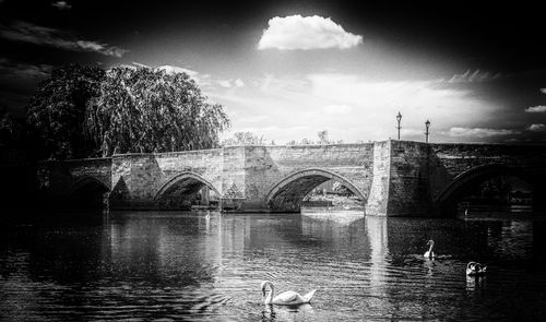 Bridge over river in city against sky