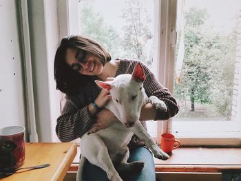 Woman with dog sitting by window
