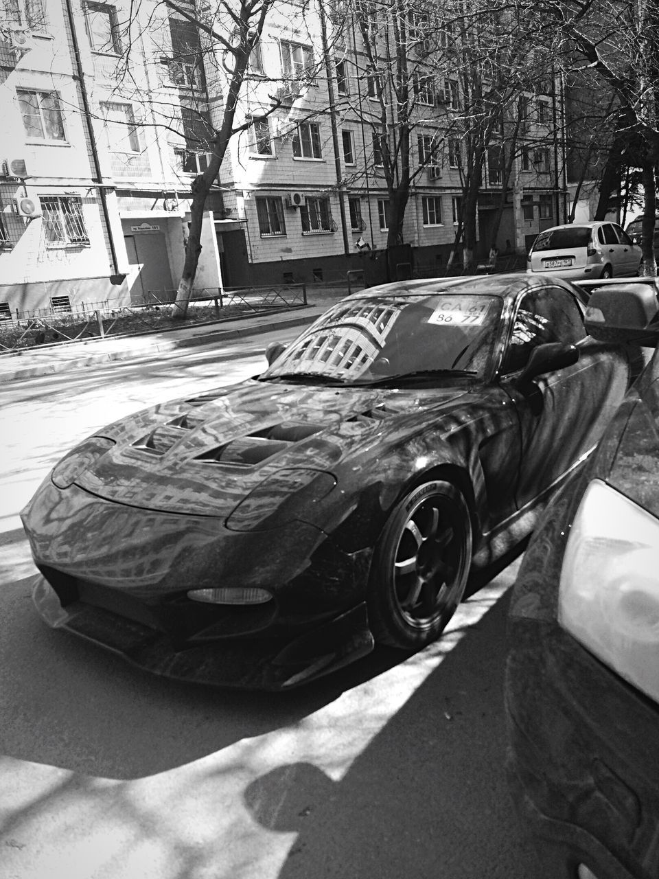 CLOSE-UP OF CAR ON STREET AGAINST CITY