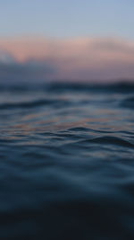 Surface level of sea against sky at sunset