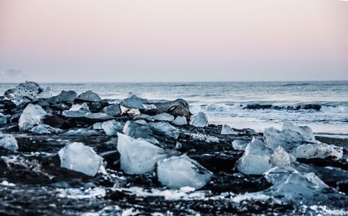 Scenic view of rocks on beach against sky