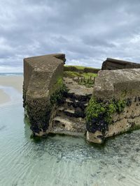 Stone wall by river against sky