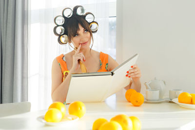 Portrait of young woman using phone while sitting on table