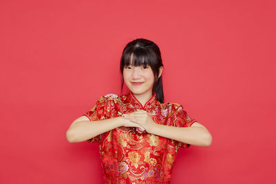 Portrait of a smiling young woman against red background