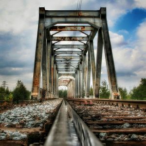 Surface level of railroad tracks against cloudy sky