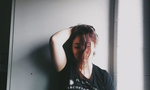 Portrait of woman standing against wall at home