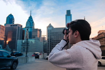 Woman photographing with cityscape in background