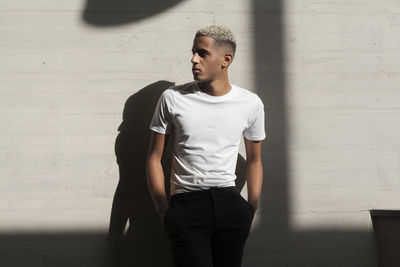 Portrait of young man standing against wall