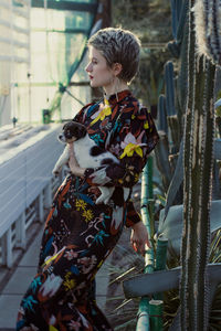 Lady in long dress holding puppy in botanic garden scenic photography