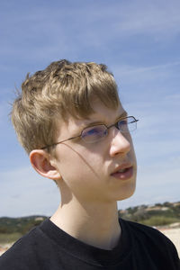 Teenage boy looking away against sky