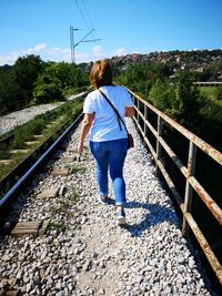 Rear view of woman walking on railroad track