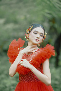 Portrait of smiling young woman standing against tree