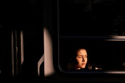 Portrait of woman looking through window at night