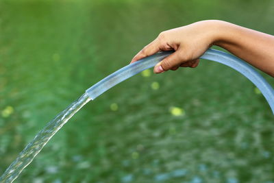 Cropped hand of woman pouring water from hose