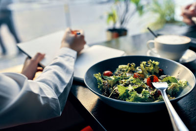 Midsection of chef writing in diary in front of food in plate