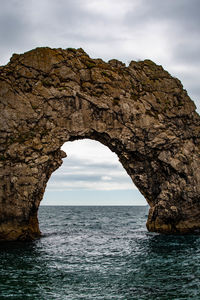 Rock formation in sea against sky