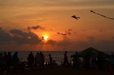 Silhouette people at beach during sunset