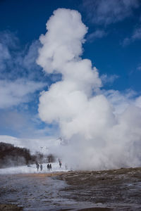 View of people on water against cloudy sky