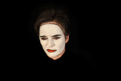 Sad man with face paint against black background