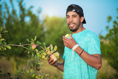 Young man smiling while standing against plants