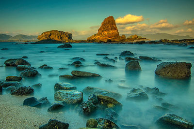 Scenic view of rocks in sea against sky