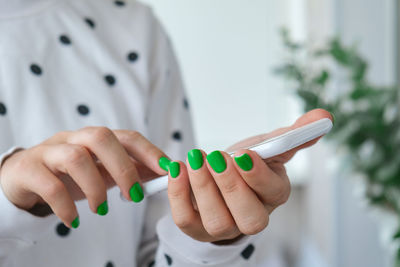 Manicured female hands with stylish green nails holding mobile phone. smartphone technology. trendy