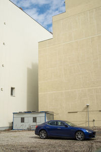 Cars parked on street by building against sky