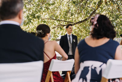 Rear view of friends standing by tree