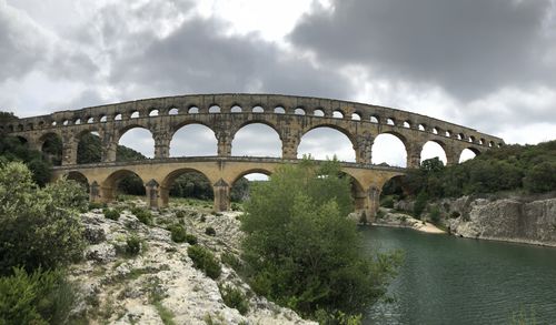 Arch bridge over river against sky