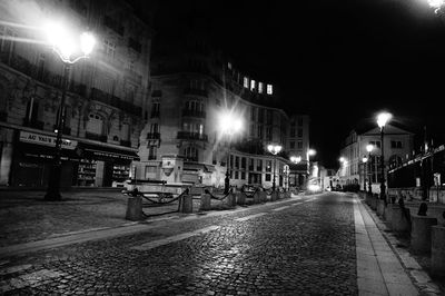 Illuminated street amidst buildings at night