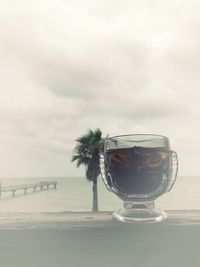 Close-up of glass on table against sea