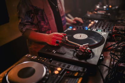 Side view of crop male dj mixing music on controller during concert in dark nightclub